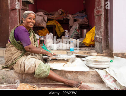 Eine glücklich lächelnde indische Frau auf der Straße machen Chapati zu verkaufen für die Kamera in Fort Kochi, Indien posieren. Stockfoto