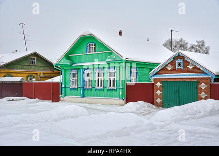 = Grün Holz- Haus mit Garage auf pushkarskaya Straße im Winter = fallenden Schnee die hellen grünen Holz- Russischen Haus mit Garage auf Pushkarskaya st Stockfoto