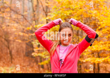 Gesunder Lebensstil Konzept. Portrait von attraktiven sportlichen lächelnde Mädchen tragen sportliche Kleidung. Frau bereiten sich auf die Ausübung im herbstlichen Wald. Stockfoto