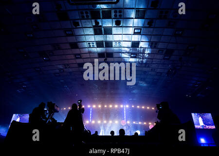 Fernsehen von einem Kameramann bei einem Konzert. Kamera mit dem Operator ist auf der Plattform. Silhouetten auf dem Hintergrund der bunte Strahl Stockfoto