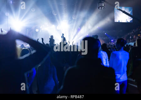 Silhouetten von einem Konzert Masse und Kameramann vor dem Hintergrund der hellen, farbigen Strahlen auf die Bühne. Kamera mit dem Operator ist auf der Pla Stockfoto