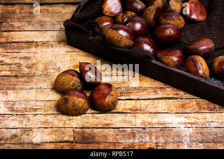 Frische Kastanien auf einem rustikalen Holztisch Stockfoto