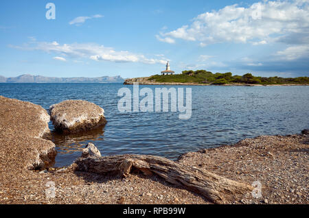 Strand mit Alcanada Leuchtturm (Faro de Alcanada) Abstand, Mallorca, Balearen, Spanien. Stockfoto