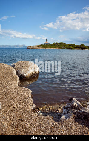 Strand mit Alcanada Leuchtturm (Faro de Alcanada) Abstand, Mallorca, Balearen, Spanien. Stockfoto