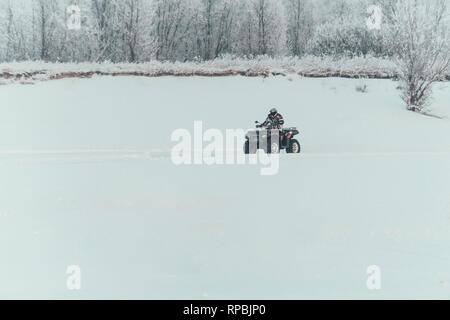 Nicht identifizierte Motocross Fahrer auf Quad Motocross saison Rennen zu öffnen. winter Motocross. ATVs sind Reiten in das Feld im Schnee auf der backgrou Stockfoto
