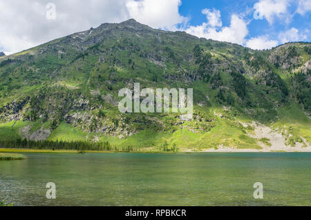 Panoramablick auf den idyllischen Sommer Landschaft in den Alpen mit klaren Bergsee und frische grüne Almen im Hintergrund Stockfoto