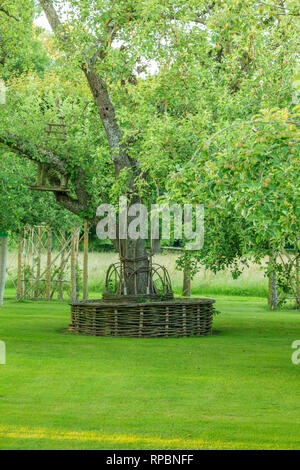 Orsan Garten, Frankreich: kreisförmige Sitzbank geflochtene um einen alten Birnbaum in der Apfelbäume Obstgarten (obligatorische Erwähnung der Garten Namen und keine Stockfoto