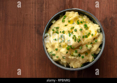 Pomme Püree, eine Schüssel mit Kartoffelbrei mit Frühlingszwiebeln und Thymian, geschossen von oben auf einen dunklen Holzmöbeln im Landhausstil Hintergrund mit Kopie Raum Stockfoto