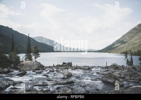 Klaren Fluss mit Felsen führt in Richtung Berge. Der Fluss fließt in den See Stockfoto