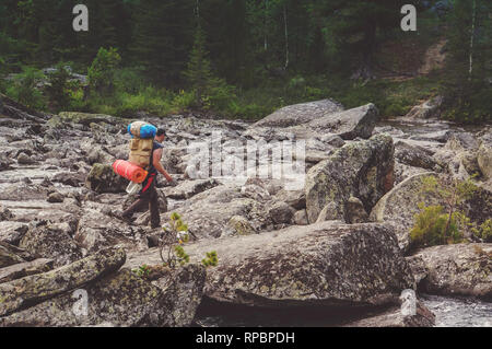 Wanderer ascenting in einem Berge. Touristen mit einem großen Rucksack am Abend durch den Stein schleichen Ablagerungen auf der Bergseite. Touristische Fußgängerzone Stockfoto