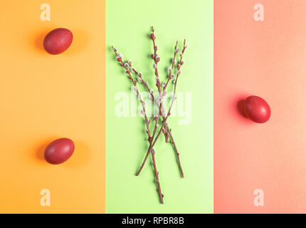 Bemalte Ostereier und Weidenzweige auf drei Farben Gelb - Grün - Coral Hintergrund. Stockfoto