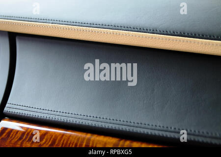Teil des Innenraums von teuren Luxuswagen. Echtes Leder Handschuhe box Panel in schwarz und beige Farbe genäht und lackiertes Holz. Stockfoto