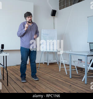 Männliche Warnung. Lehrer Achtung Studenten aus Fehlern. Mann in Freizeitkleidung. Professor Vorlesungen im Klassenzimmer mit Holzboden. Kaukasische Lehrer Stockfoto