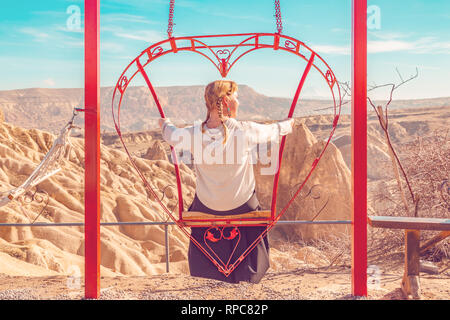 Sorglos Frau auf der Schaukel. Inspirierende Bergwelt. Traum und Freiheit Konzept. Stockfoto