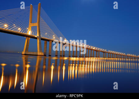 Elegante steel Bridge bei Nacht vorbei an Kilometer über große ruhige Fluss Wasser Stockfoto