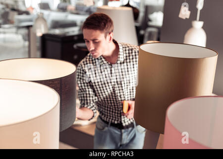 Tricenarian männliche Käufer aufmerksam die Steuerung der Lampe Qualität im Shop Stockfoto