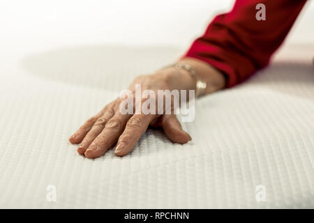 Nahaufnahme der älteren Frau, die Hand auf das Bett Tücher Stockfoto