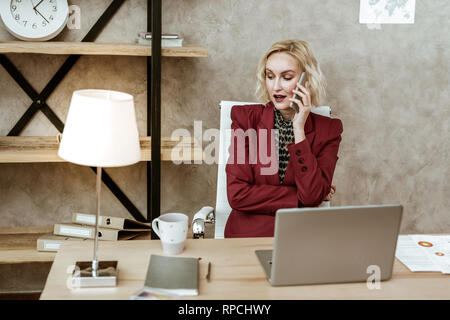 Ernsthaft beschäftigt, blonde Frau in wichtigen Anruf auf Smartphone Stockfoto