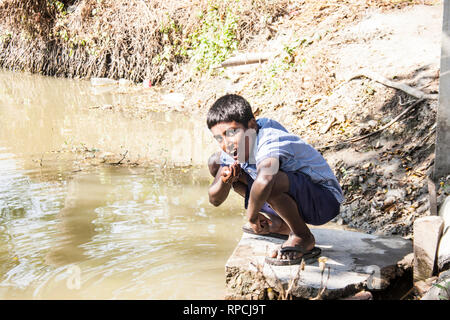 indische ländliche Schulschüler essen vor der Verwendung von Händewaschen in Teich, keshabpur Dorf, West Bengal, 1. Februar 2019 Stockfoto