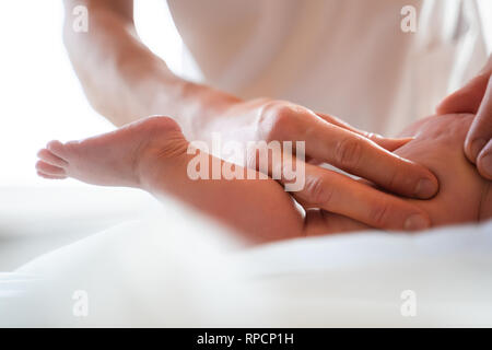 Männlichen Masseur, Bein der kleinen Kind Massage, liegen auf dem Tisch. Stockfoto