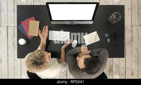 Ansicht von oben. Business Ehepaar miteinander reden und sehen Bild auf dem Bildschirm des Monitors. Weißes Display. Professionelle Aufnahme in 4K-Auflösung. 007. Sie können es z. B. Stockfoto
