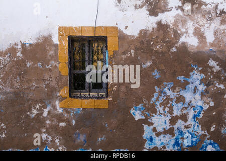 An der Wand eines alten Hauses mit Abgeschält paining der Fassade, mit blauen und weißen Farben. Gelber Rahmen des Fensters mit kunstvollen Gitter. Straße von Safi, Stockfoto