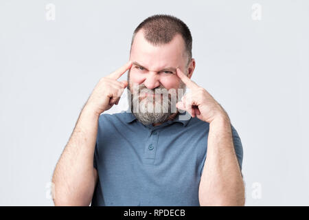 Mann mit Bart hält Finger auf Tempel und versuchte, an etwas zu erinnern. Stockfoto