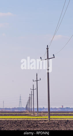 Alte power transmission Towers im Einklang mit blauem Himmel und die Stadt im Hintergrund Stockfoto