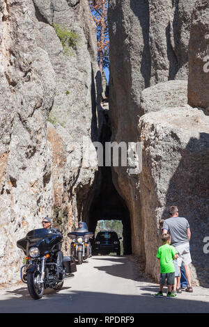 CUSTER STATE PARK in South Dakota - Juni 9, 2014: Nadeln Auge Tunnel mit Motorräder und ein Auto fahren durch und eine Familie in den Tunnel auf der Suche Stockfoto