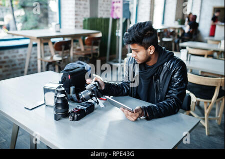 Smart junger asiatischer Mann Fotografen arbeiten mit Tablette während der Sitzung im Cafe. Stockfoto