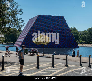 Ein multikulturelles Publikum mit muslimischen Frauen in Burka Kopftuch jihab Radfahrer entspannende Sitzung Wandern Radfahren Hyde Park Serpentine Mastaba Stockfoto