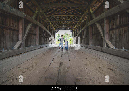 Brüder spielen im Inneren eine überdachte Brücke Stockfoto