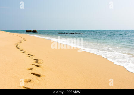 Fuß Ausdrucke in einer goldenen Sand klar perfekte Strand neben einem ruhigen türkisfarbenen Meer. Stockfoto