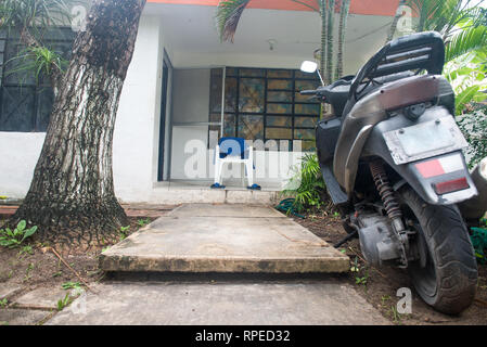 Weiß chear mit dem blauen Handtuch und blauen Flip Flops auf der Veranda des Hauses. Tropische Natur rund um Motorrad auf den ersten Plan und. Konzept der Lateinischen EIN Stockfoto