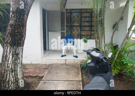 Weiß chear mit dem blauen Handtuch und blauen Flip Flops auf der Veranda des Hauses. Tropische Natur rund um Motorrad auf den ersten Plan und. Konzept der Lateinischen EIN Stockfoto