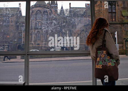 Frau wartet auf den Bus vor der University of Glasgow, Schottland, Großbritannien Stockfoto