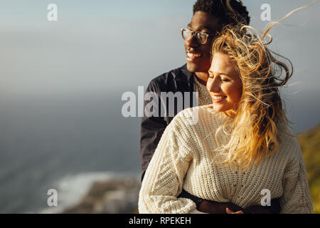 Romantisches Paar genießt jeder des anderen Firma auf ihren Urlaub. Mann, der seine Frau umarmt von hinten und sowohl die Aussicht genossen. Stockfoto