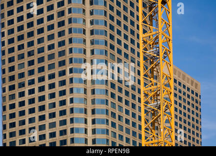 Teilweise mit Blick auf ein modernes Glas und Beton architektonischen Stil Office Tower Gebäude und Gelb arbeiten Kran Stockfoto
