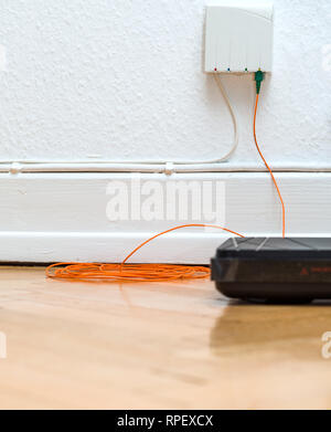 Detail der LWL-Installation zu Hause mit veralteten CATV- und neue FTTH Fibre Outlets und internet Receiver auf Parkettboden Stockfoto