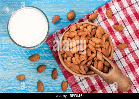 Mandel Milch in ein Glas und Mandeln in einer Schüssel auf Blau Holz- Hintergrund. Ansicht von oben Stockfoto