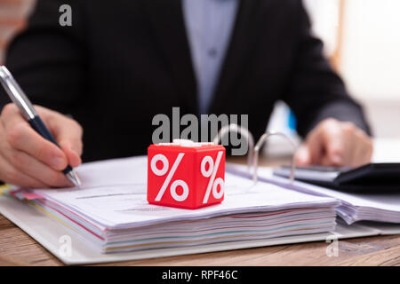 Nahaufnahme von roten Kubische Block mit prozentualer Symbol Vor Unternehmer Berechnung Rechnung Stockfoto