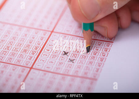 Nahaufnahme einer Person Nummer auf Lottoschein mit Bleistift markieren Stockfoto