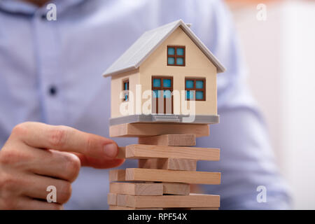 In der Nähe von einem Geschäftsmann Hand Entfernen von hölzernen Blöcke mit Modell Haus Stockfoto