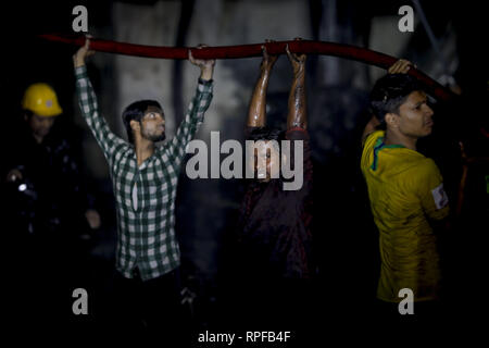 Dhaka, Bangladesch. 21 Feb, 2019. Bewohner helfen, ein Schlauch als Feuerwehrmänner kämpften Flammen zu kontrollieren. Credit: KM Asad/ZUMA Draht/Alamy leben Nachrichten Stockfoto