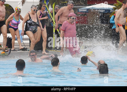 Karlsruhe, Deutschland. 22 Feb, 2019. Besucher des Open-air Swimming pool onnenbad' Sprung ins Wasser des Pools für die Eröffnung der Open-Air-Swimmingpool. Nach dem städtischen Schwimmbad Unternehmen, das Bad ist die erste Outdoor Pool in Deutschland zurück aus der Winterpause zu berichten. Egal wie kalt es ist: Sie können planschen und schwimmen außerhalb bei einer Wassertemperatur von über 28 Grad bis zum 1.Advent. Das Motto für die diesjährige Saison ist "Wer schwimmen außerhalb fit bleiben". Credit: Uli Deck / dpa/Alamy leben Nachrichten Stockfoto