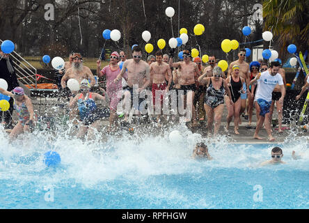 Karlsruhe, Deutschland. 22 Feb, 2019. Besucher des Open-air Swimming pool onnenbad' Sprung ins Wasser des Pools für die Eröffnung der Open-Air-Swimmingpool. Nach dem städtischen Schwimmbad Unternehmen, das Bad ist die erste Outdoor Pool in Deutschland zurück aus der Winterpause zu berichten. Egal wie kalt es ist: Sie können planschen und schwimmen außerhalb bei einer Wassertemperatur von über 28 Grad bis zum 1.Advent. Das Motto für die diesjährige Saison ist "Wer schwimmen außerhalb fit bleiben". Credit: Uli Deck / dpa/Alamy leben Nachrichten Stockfoto