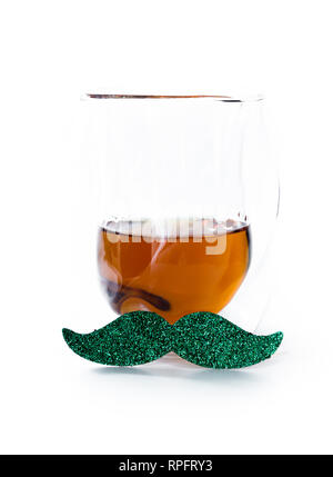 Konzept für Saint Patricks Day mit einem Glas Whiskey serviert ordentlich mit einem grünen Schnurrbart auf weißem Hintergrund Stockfoto