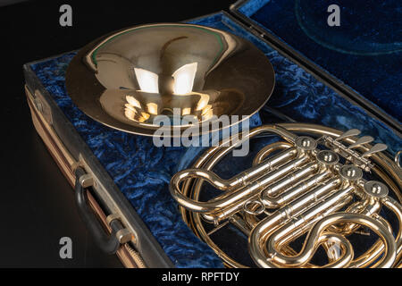 Horn in einem alten Fall auf einem Holztisch. Schöne polierte Musikinstrument. Der dunkle Hintergrund. Stockfoto