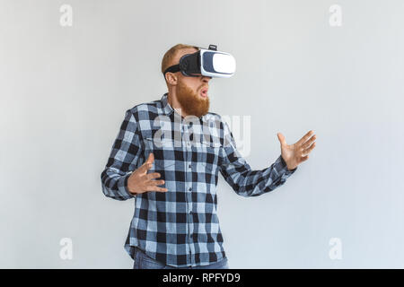 Freestyle. Reifer Mann in virtual reality Headset stehen isoliert auf grau Spielen aufgeregt Stockfoto