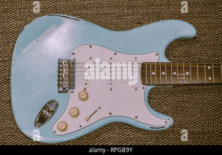 Hellblau E-Gitarre in eine Textur Hintergrund. Alter abgenutzte Gitarre Stockfoto